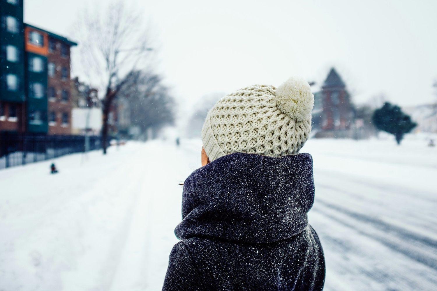 Junge Frau mit Mütze, die in einer Winterlandschaft spazieren geht
