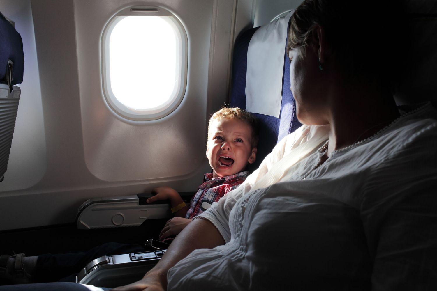 Ein Kind weint, weil es im Flugzeug Druck auf den Ohren spürt