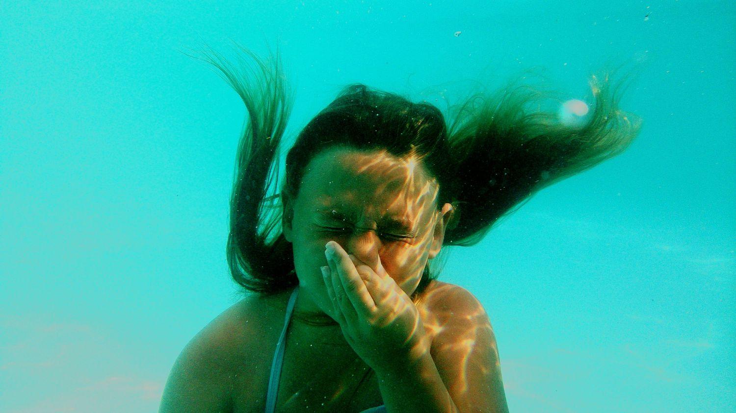 Ein Mädchen macht das Valsalva Manöver unter Wasser