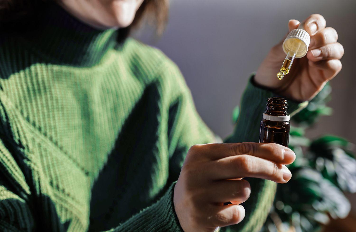 Aufnahme von einer Frau, die eine Pipetten Flasche mit Öl zum Ohrenschmalz entfernen in den Händen hat.