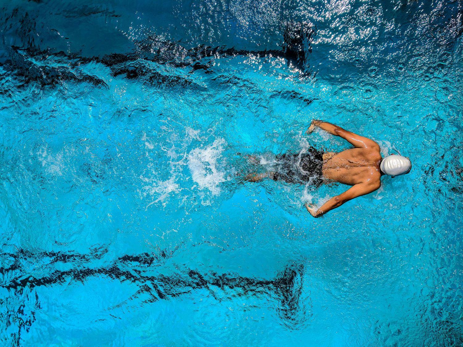 Mann, der in einem Pool schwimmt und Wasser im Ohr hat